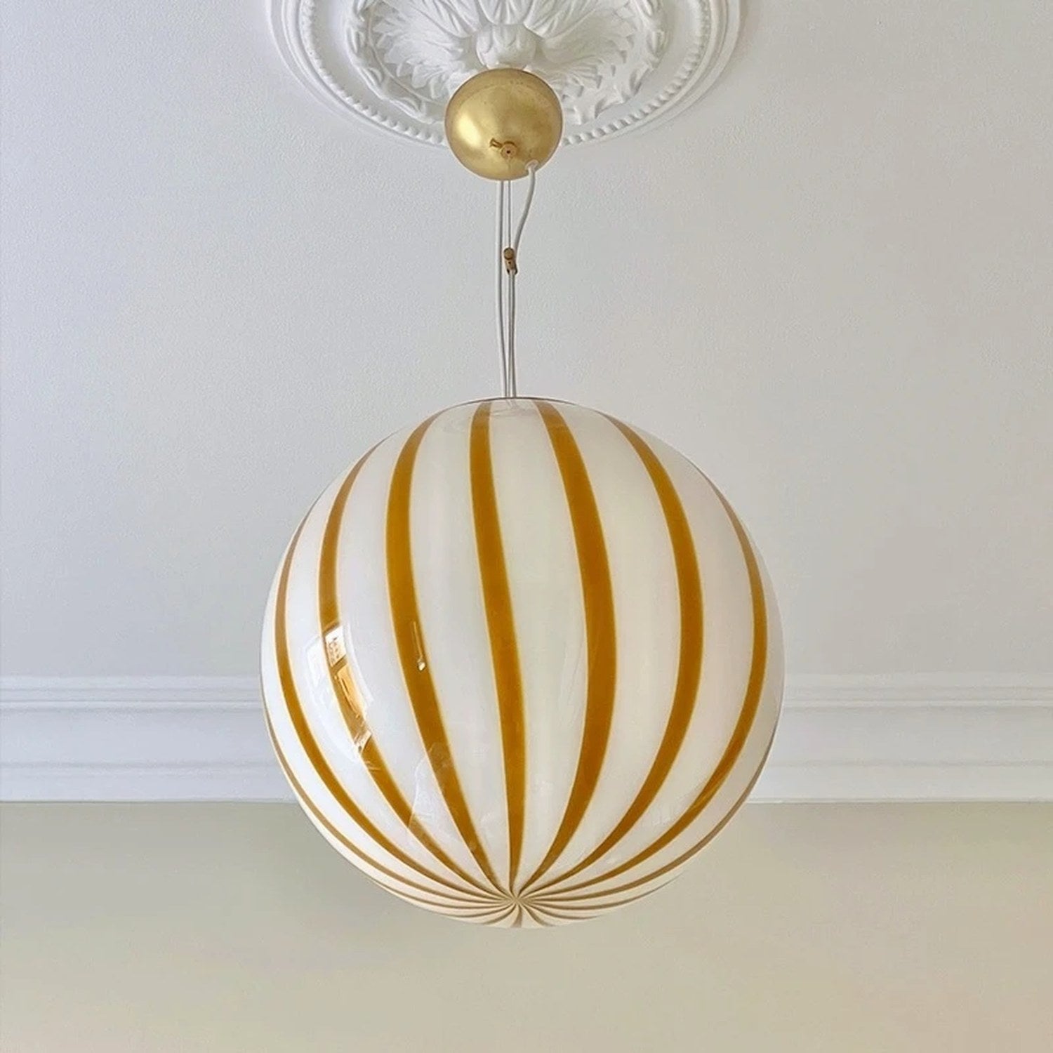 Suspension boule en verre rayée jaune vue de près