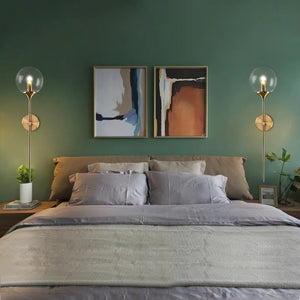 Paire d'appliques murales ambrées de part et d'autre d'un lit dans une chambre verte