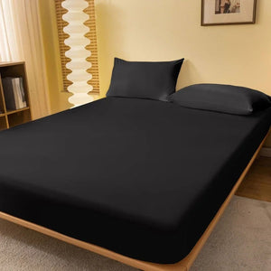 Drap housse noir ajusté sur un lit fait dans une chambre chaude et lumineuse