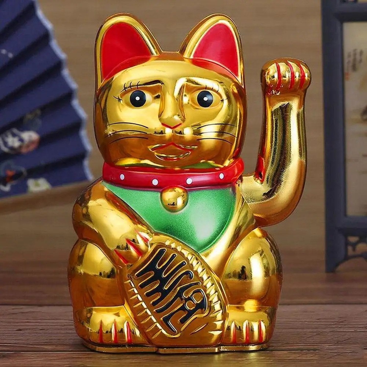 Figurine chat porte-bonheur doré posée sur une surface en bois avec décoration asiatique
