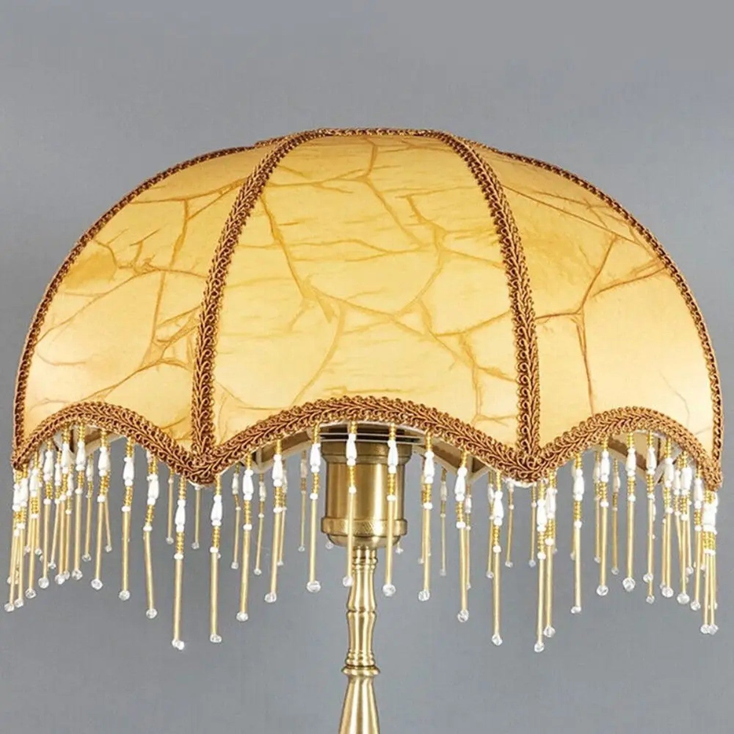 Abat-jour rétro doré sur lampadaire laiton, fond gris neutre