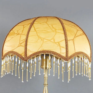 Abat-jour rétro doré sur lampadaire laiton, fond gris neutre