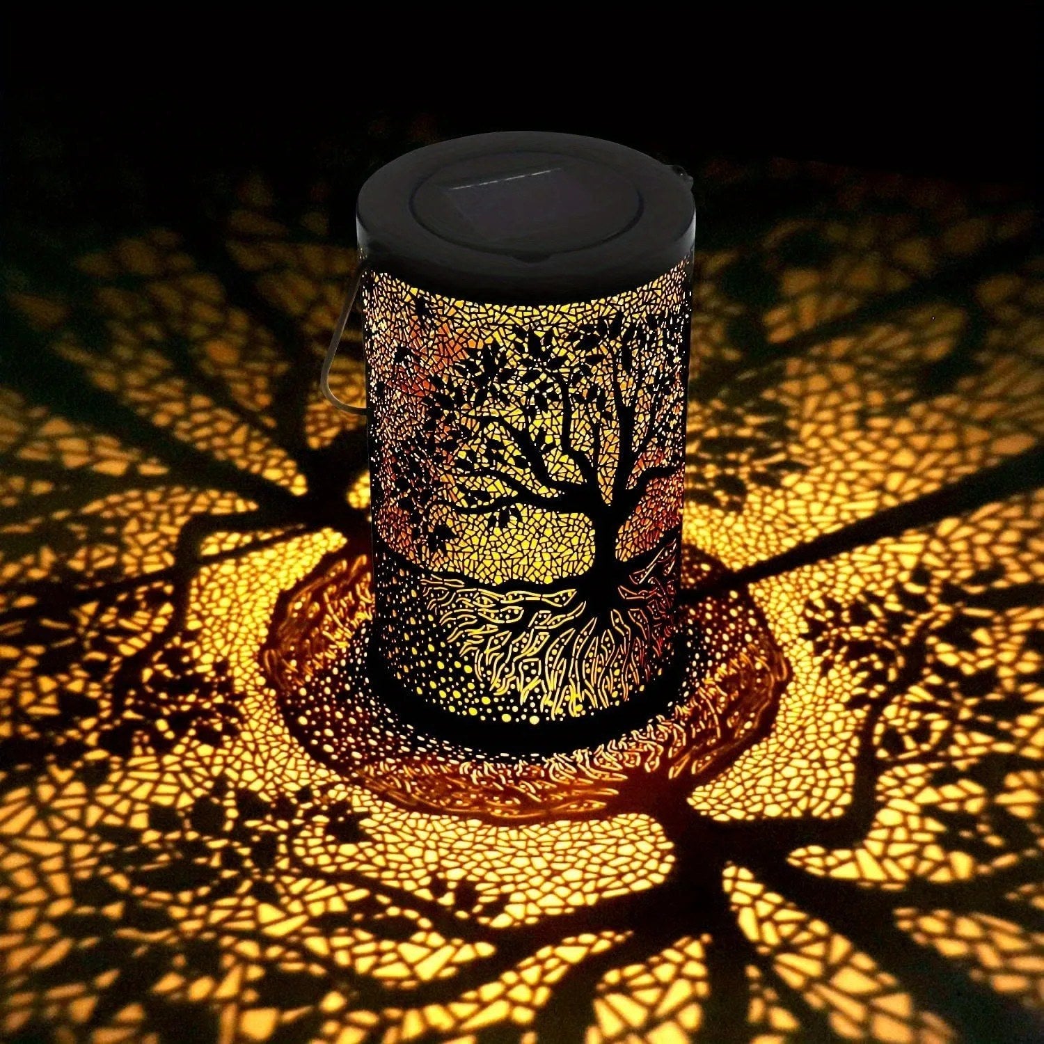 Lanterne solaire arbre de vie allumée projetant une ombre en mosaïque dorée au sol