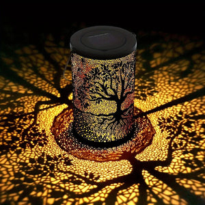 Lanterne solaire arbre de vie allumée projetant une ombre en mosaïque dorée au sol