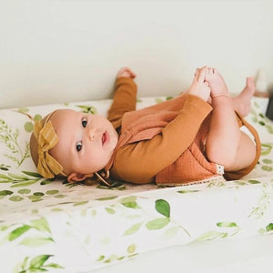 Photo réelle d'un bébé allongé sur la housse de matelas à langer motif feuillage