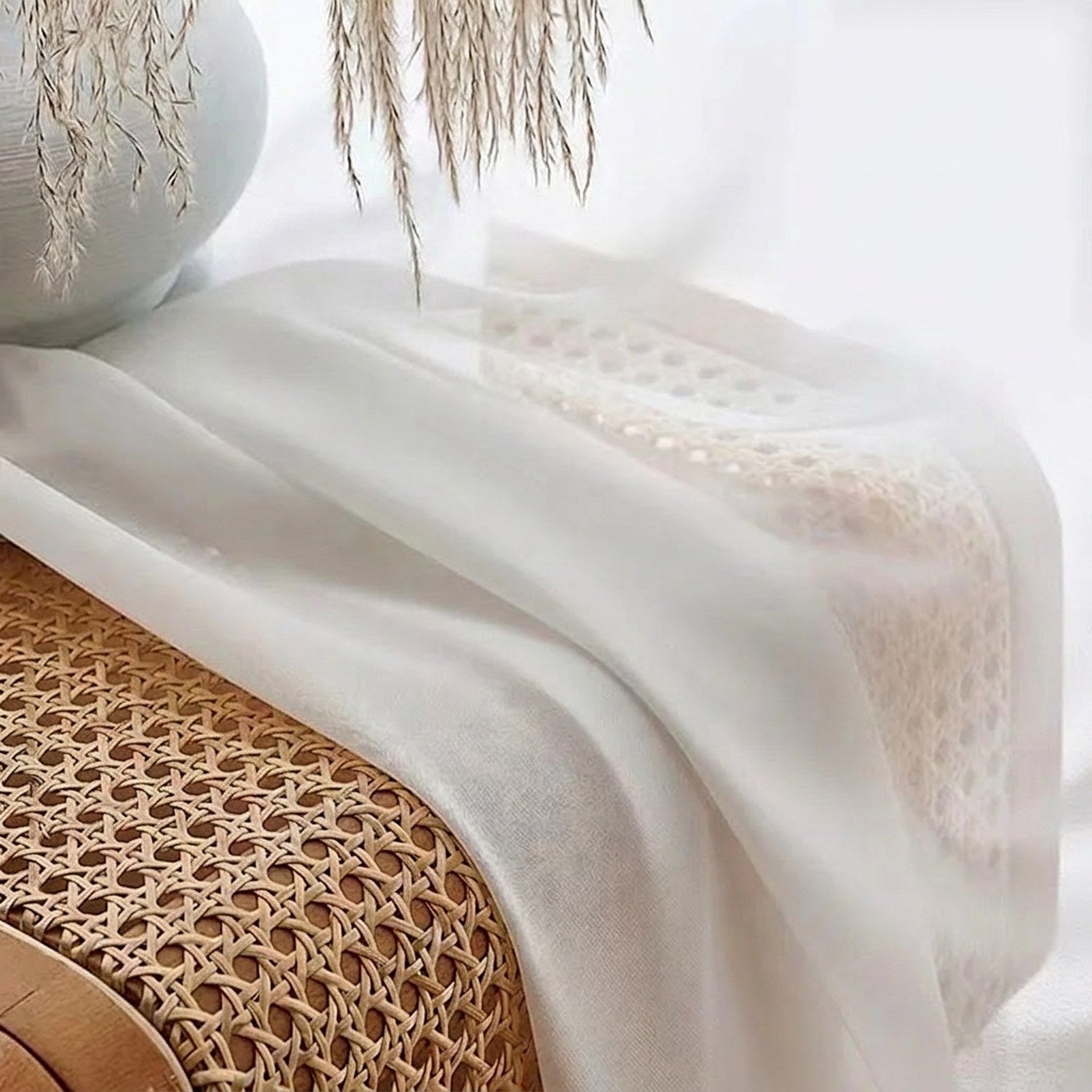 Détail du tissu voile blanc posé sur un banc en rotin