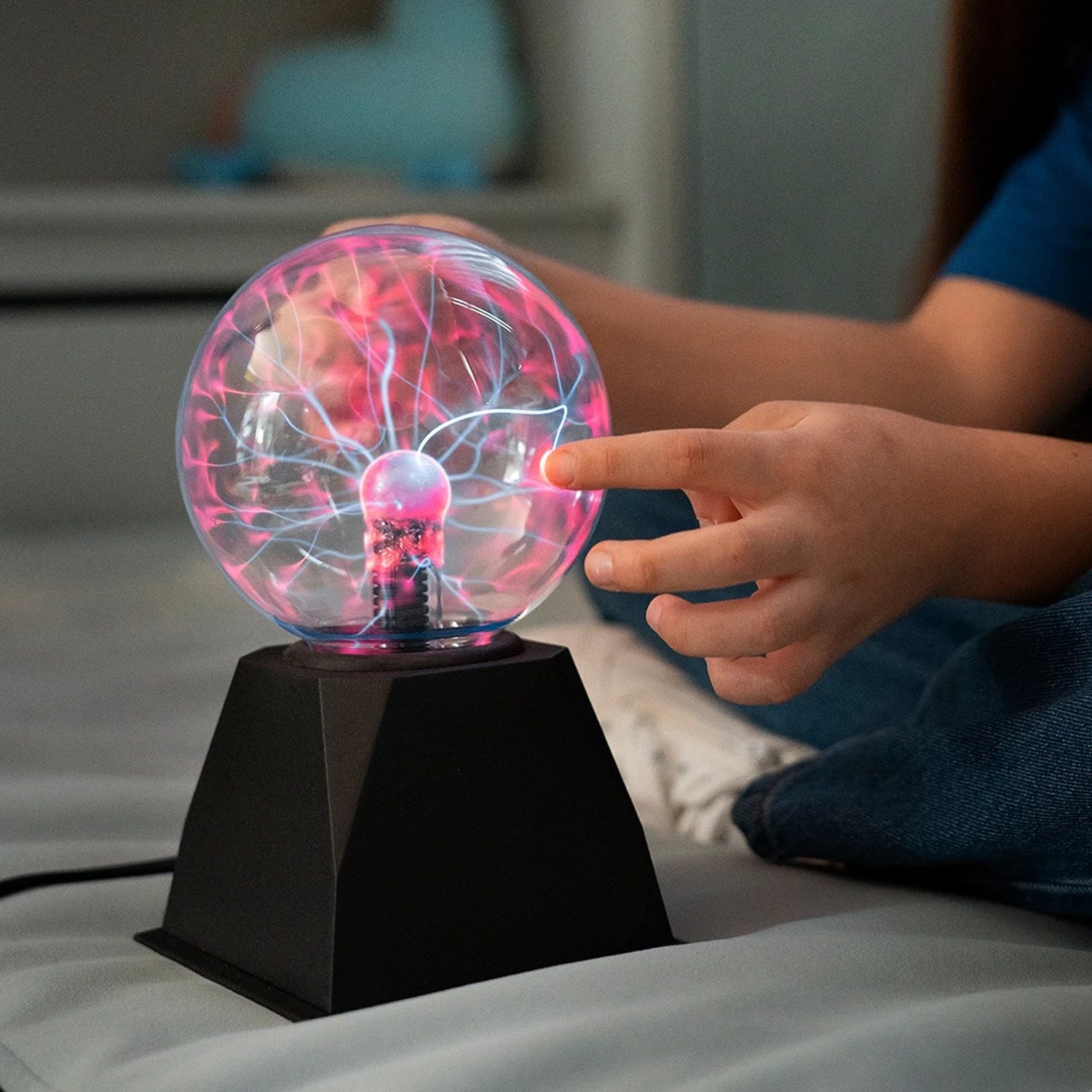 Enfant touchant du doigt une lampe boule de plasma allumée
