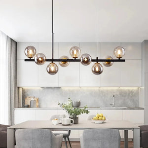 Lustre noir à globes de verre ambré suspendu au dessus d'une table à manger