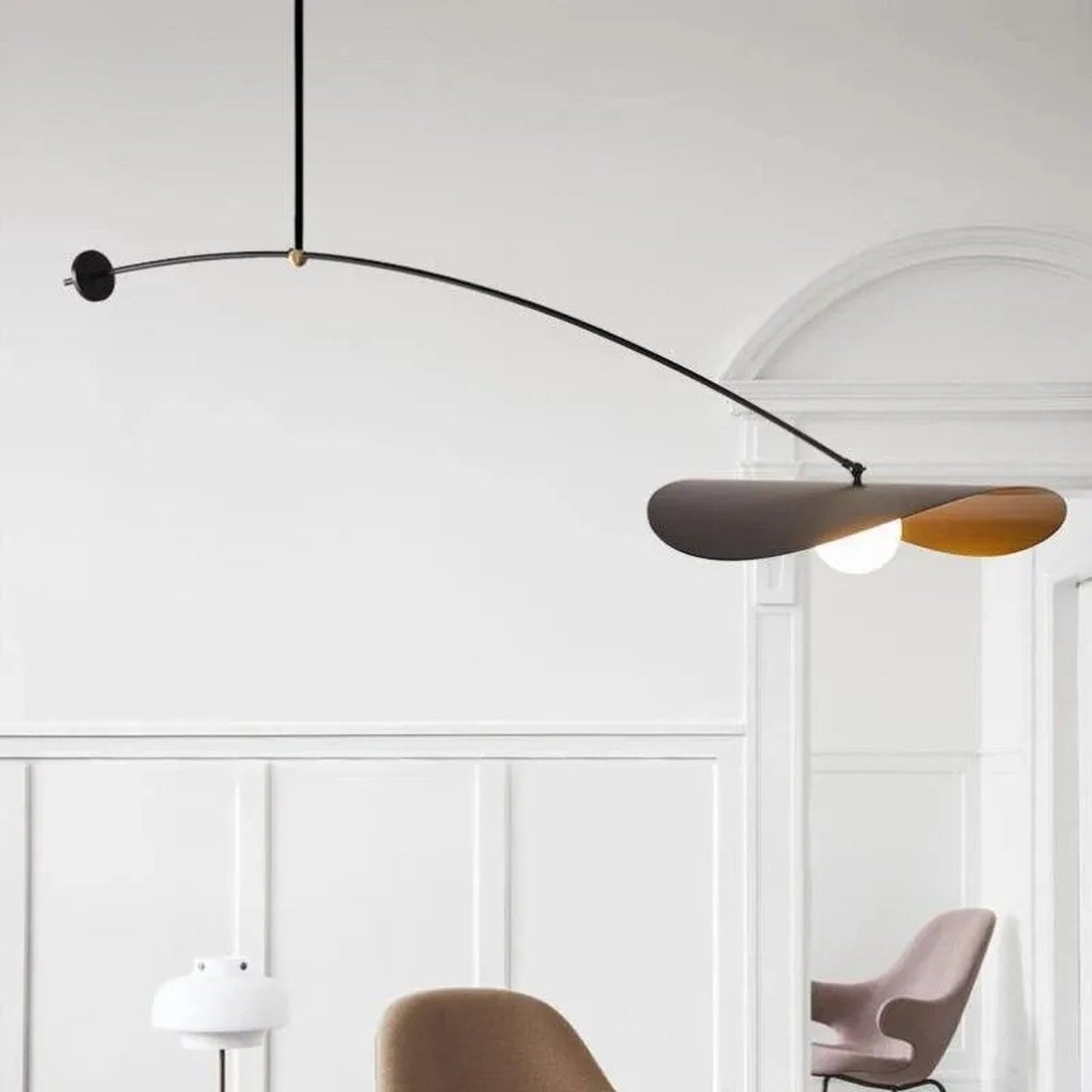 Suspension au bras arqué long éclairant un salon aux boiseries blanches