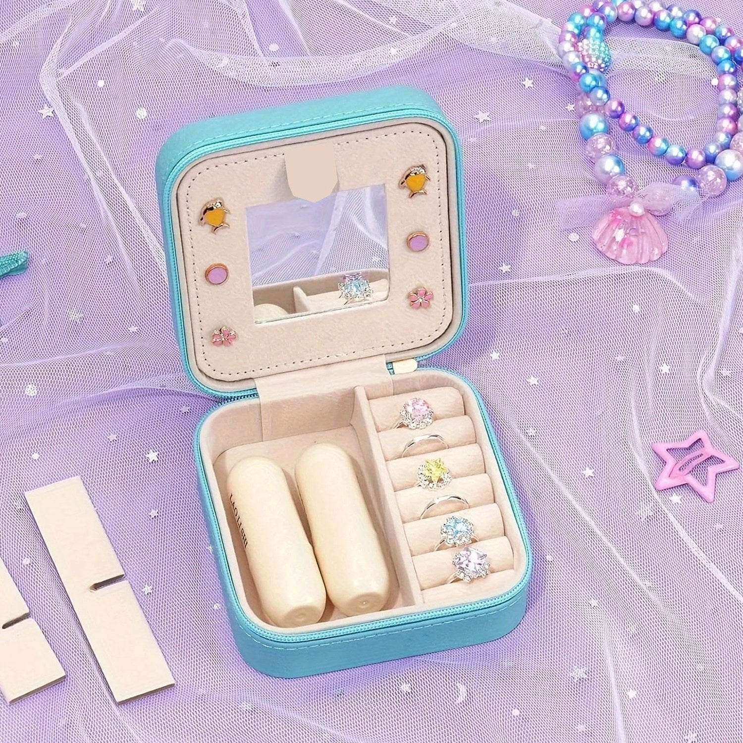 Boîte à bijoux sirène bleue ouverte sur surface lilas avec bracelet perles à côté