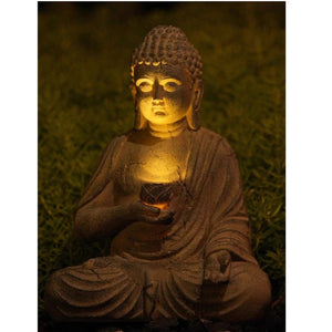 Statue Bouddha résine de nuit avec lumière solaire chaude sur visage serein dans le jardin