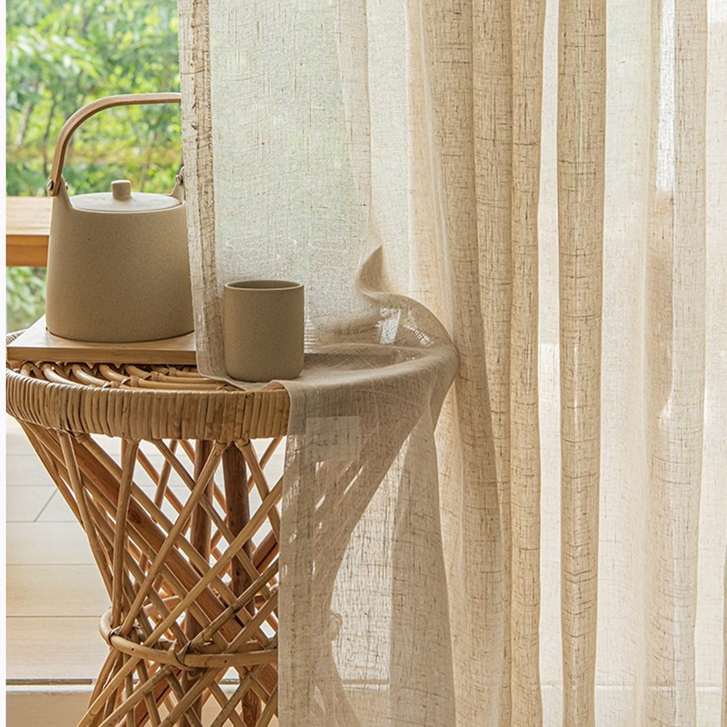 Détail du tissu tulle façon lin posé sur une table en rotin avec théière en céramique