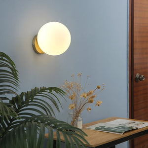 Applique murale boule de verre dorée dans un intérieur avec plante verte
