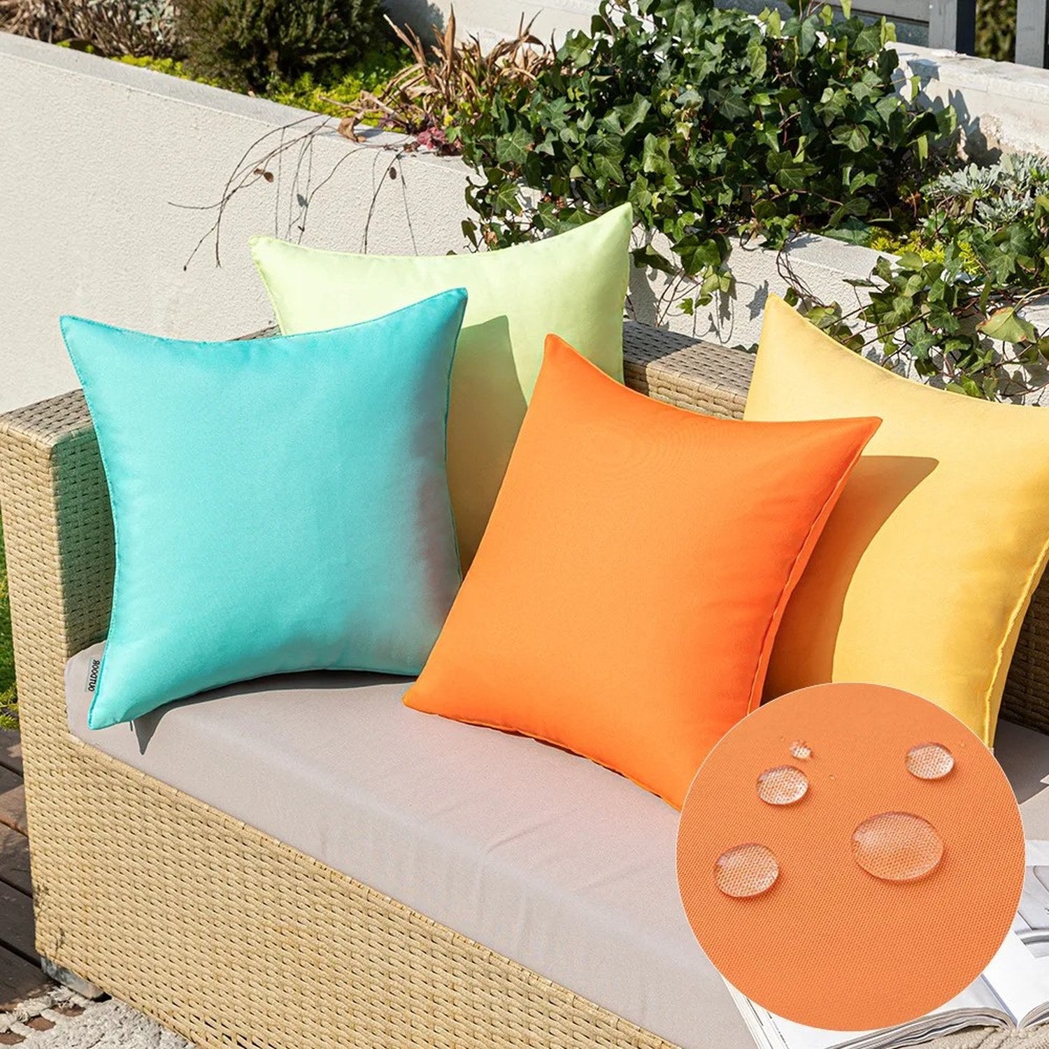 Housses de coussin extérieur colorées sur un canapé en rotin avec zoom sur des gouttes d'eau montrant le tissu imperméable