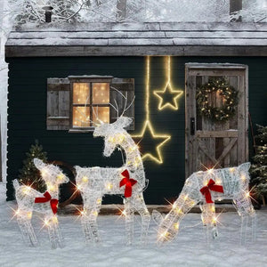 Cerfs lumineux de Noël en métal dans la neige devant une maison