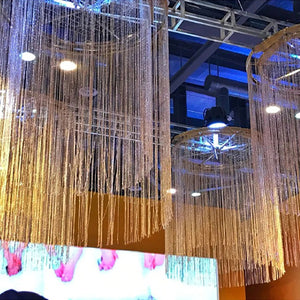 Rideaux à fils suspendus formant des colonnes lumineuses dans un espace évènementiel