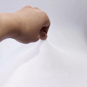 Main tendant le tissu extensible blanc de la housse de chaise pour montrer son élasticité