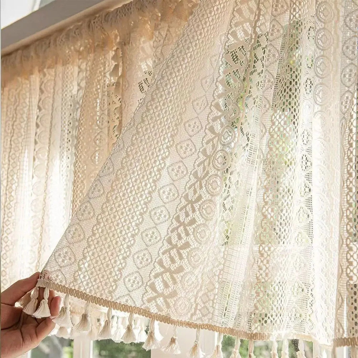 Rideau dentelle beige tenu à la main devant une fenêtre