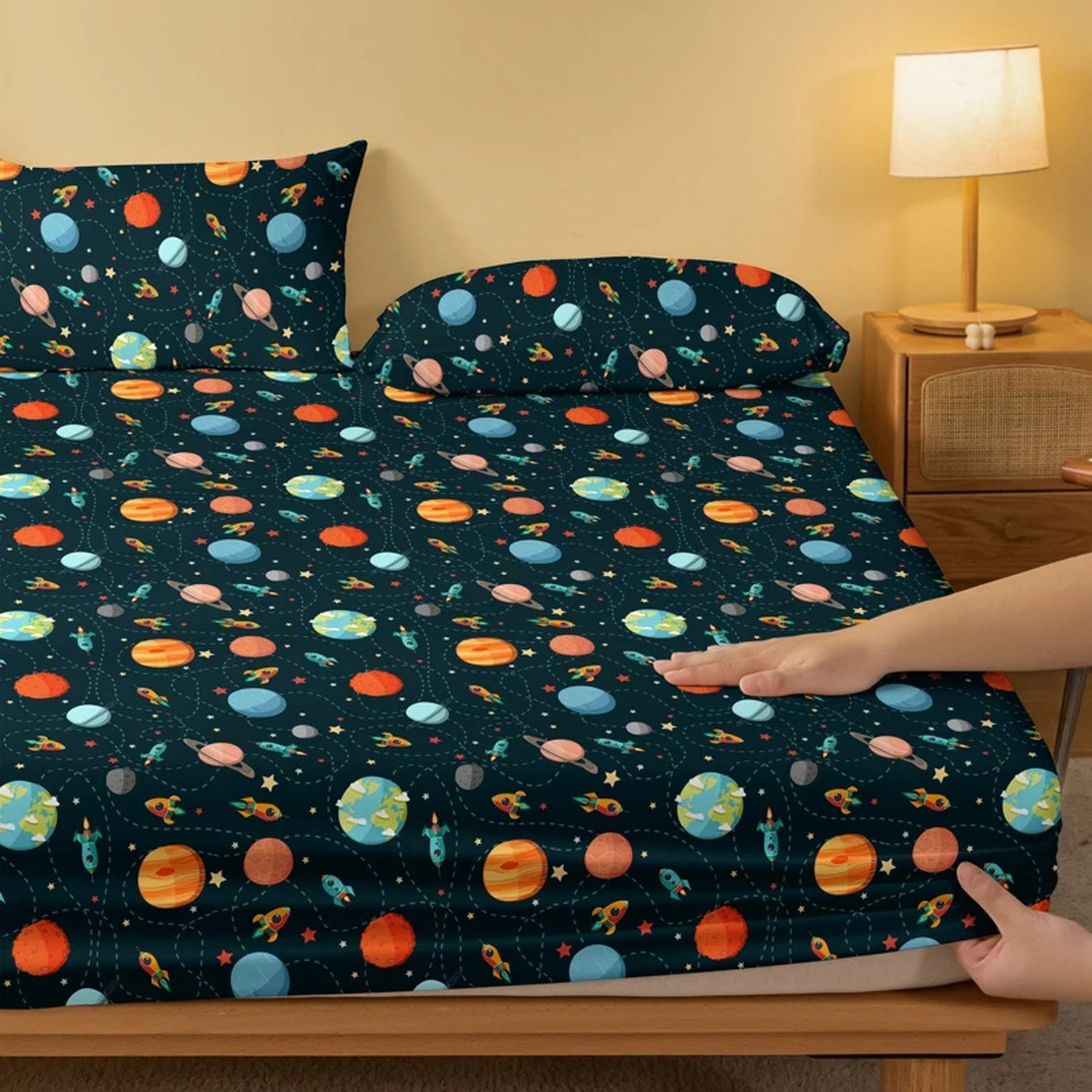 Drap housse cosmos sur un lit avec table de chevet en bois et lampe allumée