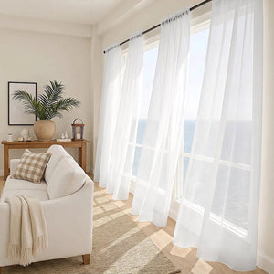 Voilage blanc filtrant la lumière dans un salon avec vue sur la mer
