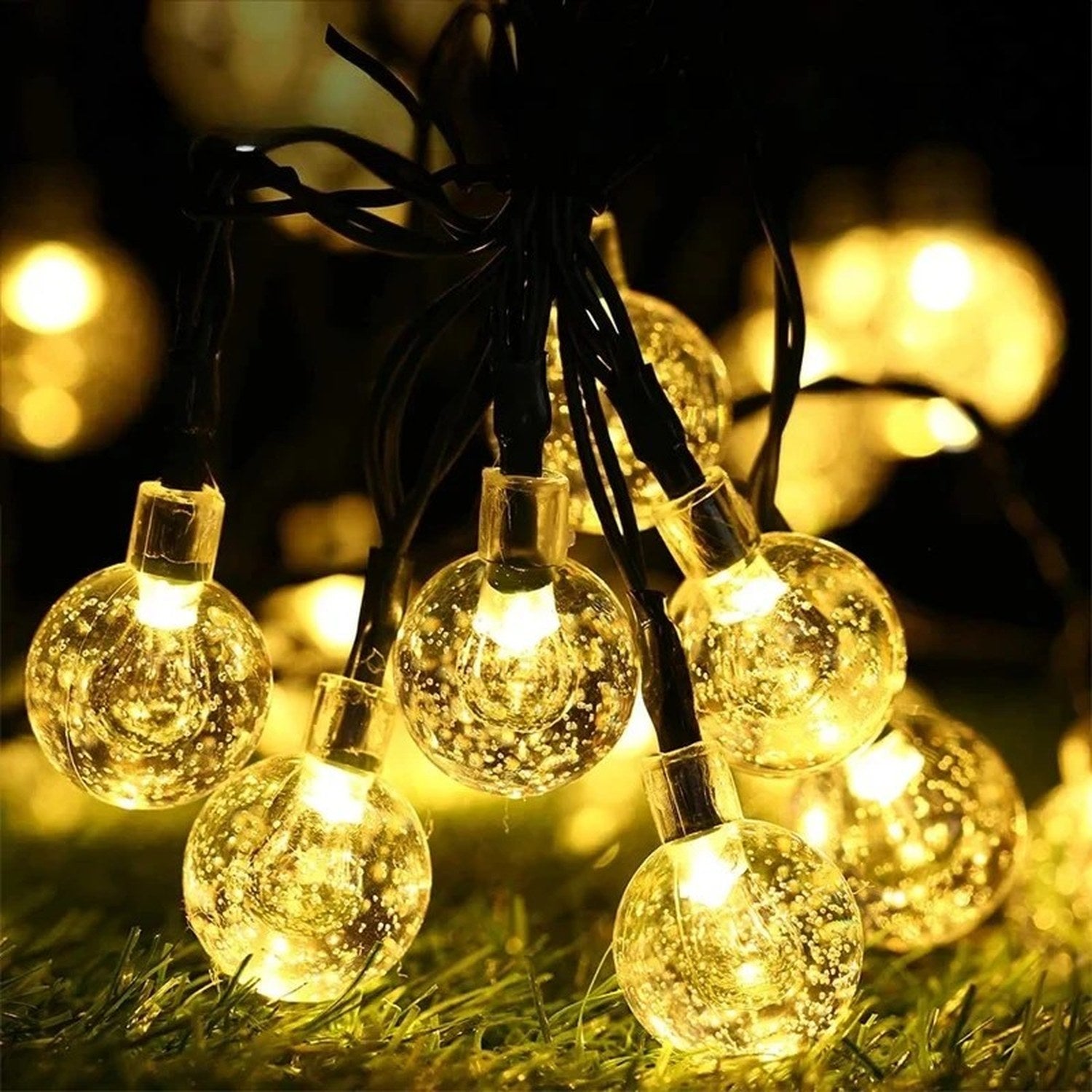 Globes de cristal LED allumés sur gazon vert la nuit