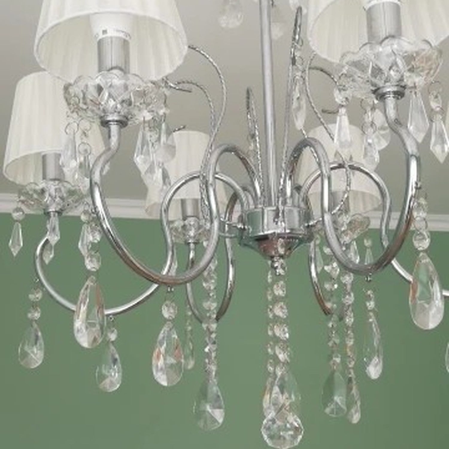 Lustre pampilles avec abat-jours blancs plissés dans salon vert décoration