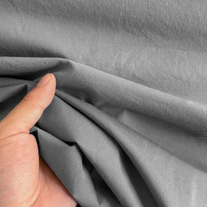 Gros plan sur la texture du tissu en coton gris tenu à la main