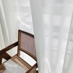 Voilage blanc drapé près d'une chaise en bois et rotin