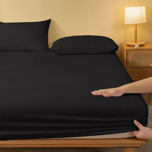Drap housse noir sur un lit avec table de chevet et lampe allumée