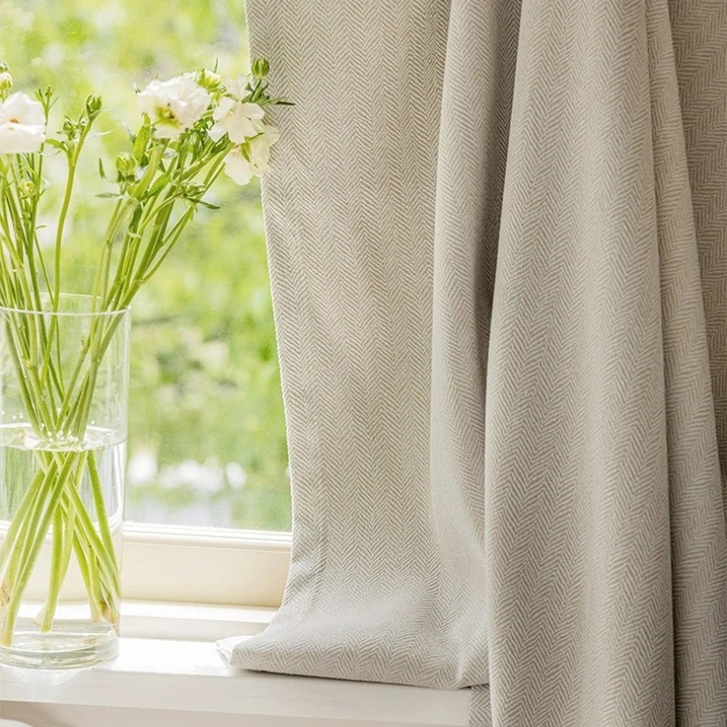 Détail de la texture chevrons du rideau chenille près d'une fenêtre avec fleurs