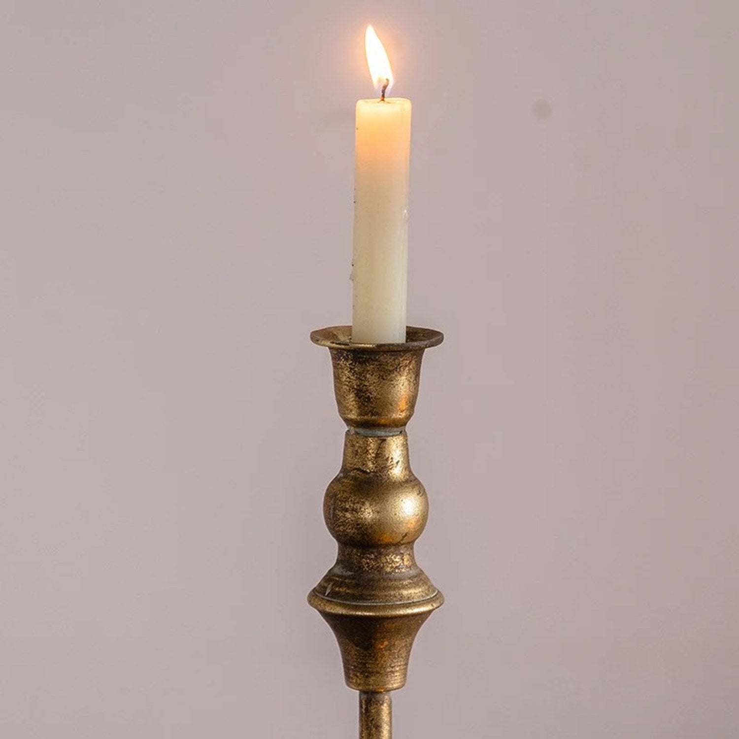 Gros plan sur la bougie allumée et la finition laiton antique du chandelier