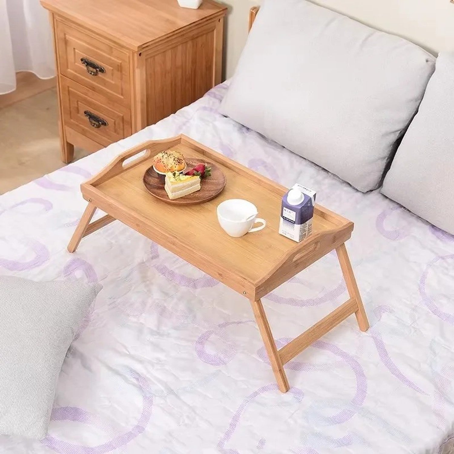 Plateau bambou sur lit avec petit déjeuner brioché tasse et jus posés dessus