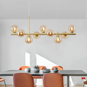 Lustre doré à globes de verre ambré au dessus d'une table entourée de chaises terracotta