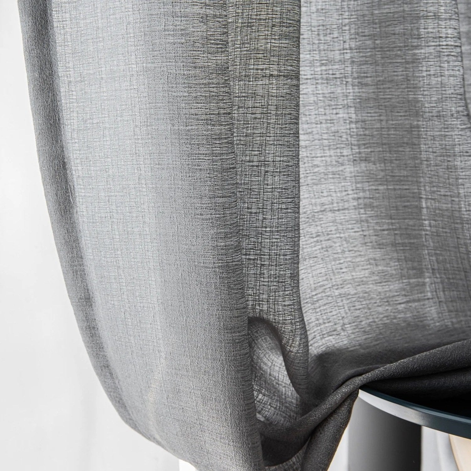 Détail du tissage gris du rideau laissant filtrer la lumière