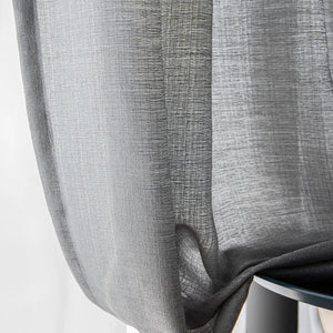 Détail du tissage gris du rideau laissant filtrer la lumière