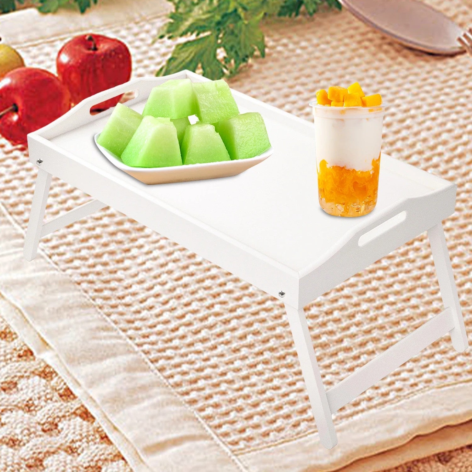 Plateau bambou naturel sur un lit présentant des fruits frais et une boisson fraîche