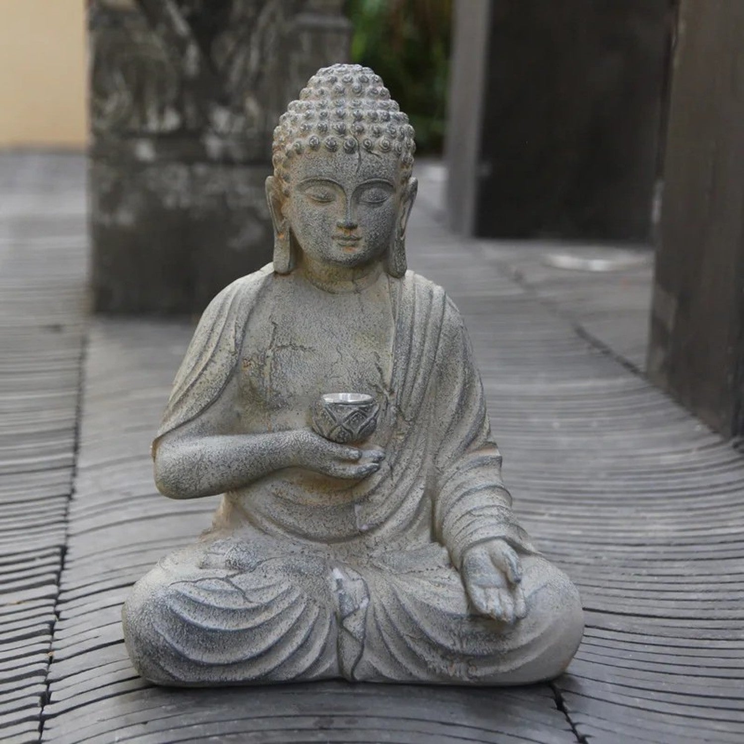 Statue Bouddha résine posée sur terrasse en bois dans un jardin japonais