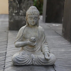 Statue Bouddha résine posée sur terrasse en bois dans un jardin japonais