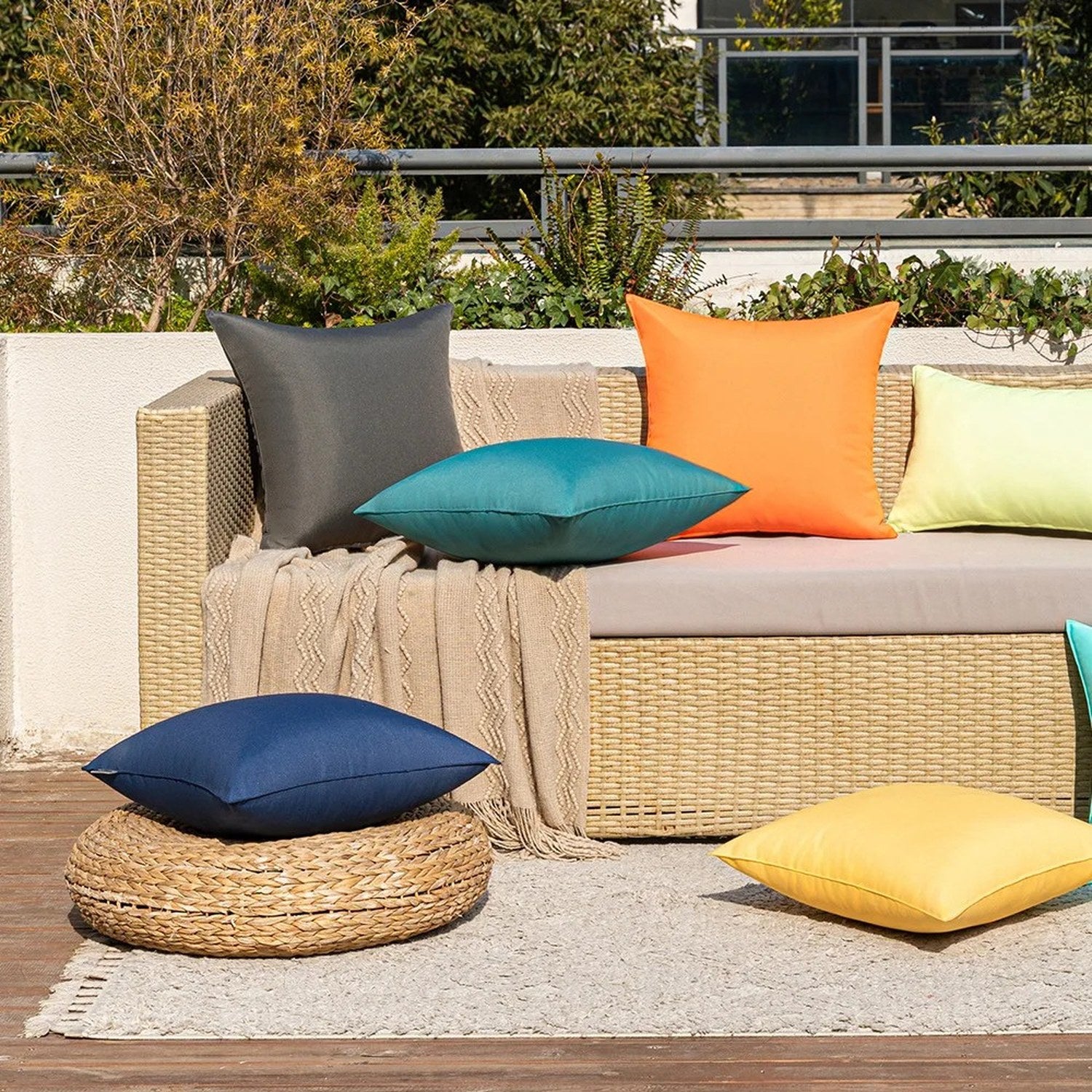 Housses de coussin extérieur colorées sur un canapé en rotin sur une terrasse en ville