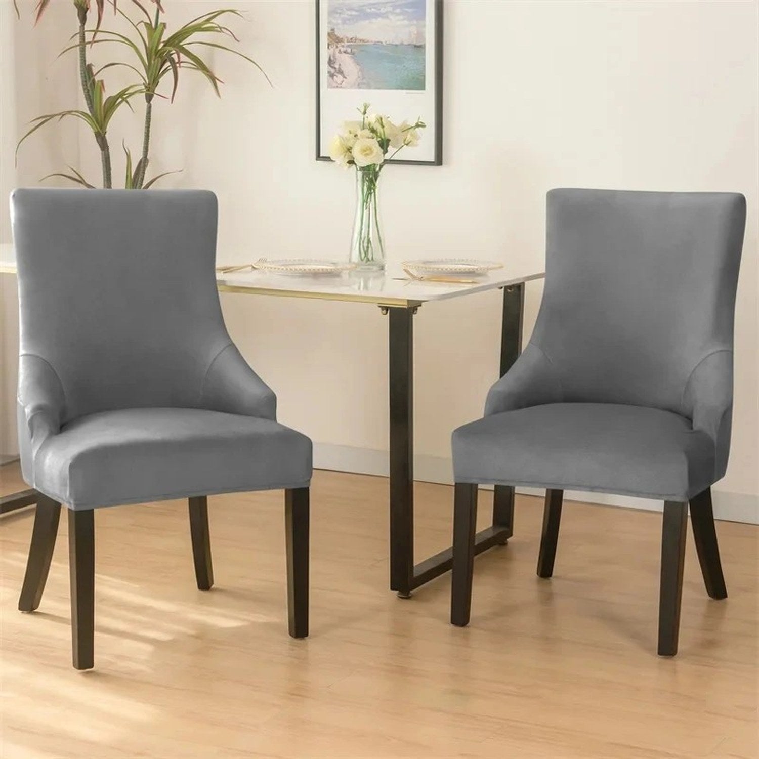 Chaises de salle à manger grises en velours autour d une table avec décoration murale