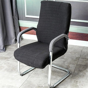 Housse d'accoudoir noire installée sur une chaise de bureau dans un intérieur moderne