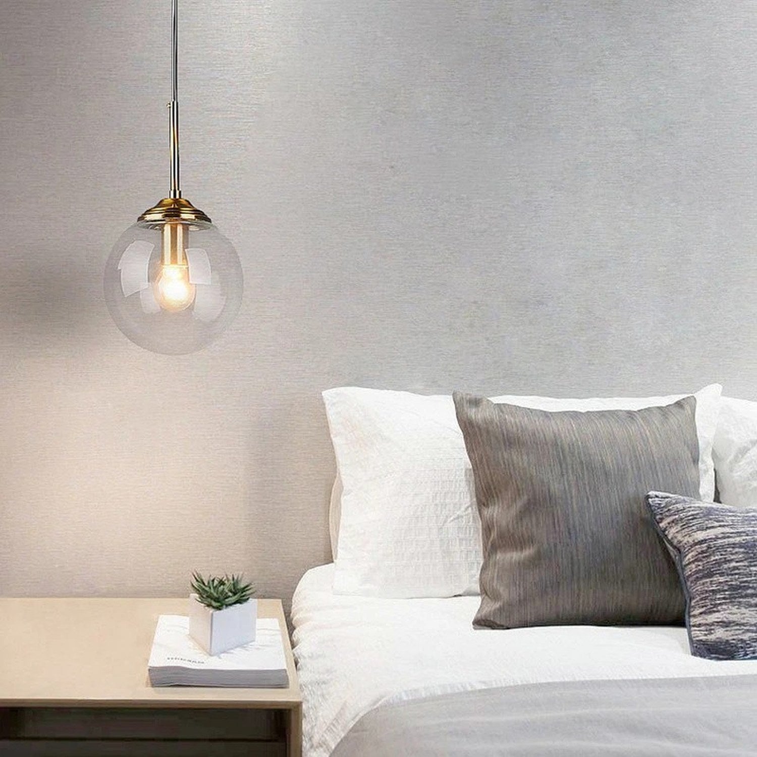 Suspension globe en verre transparent au-dessus chevet chambre nordique minimaliste