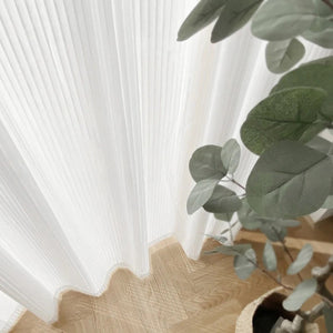 Plis du voilage blanc en gros plan avec une branche d'eucalyptus