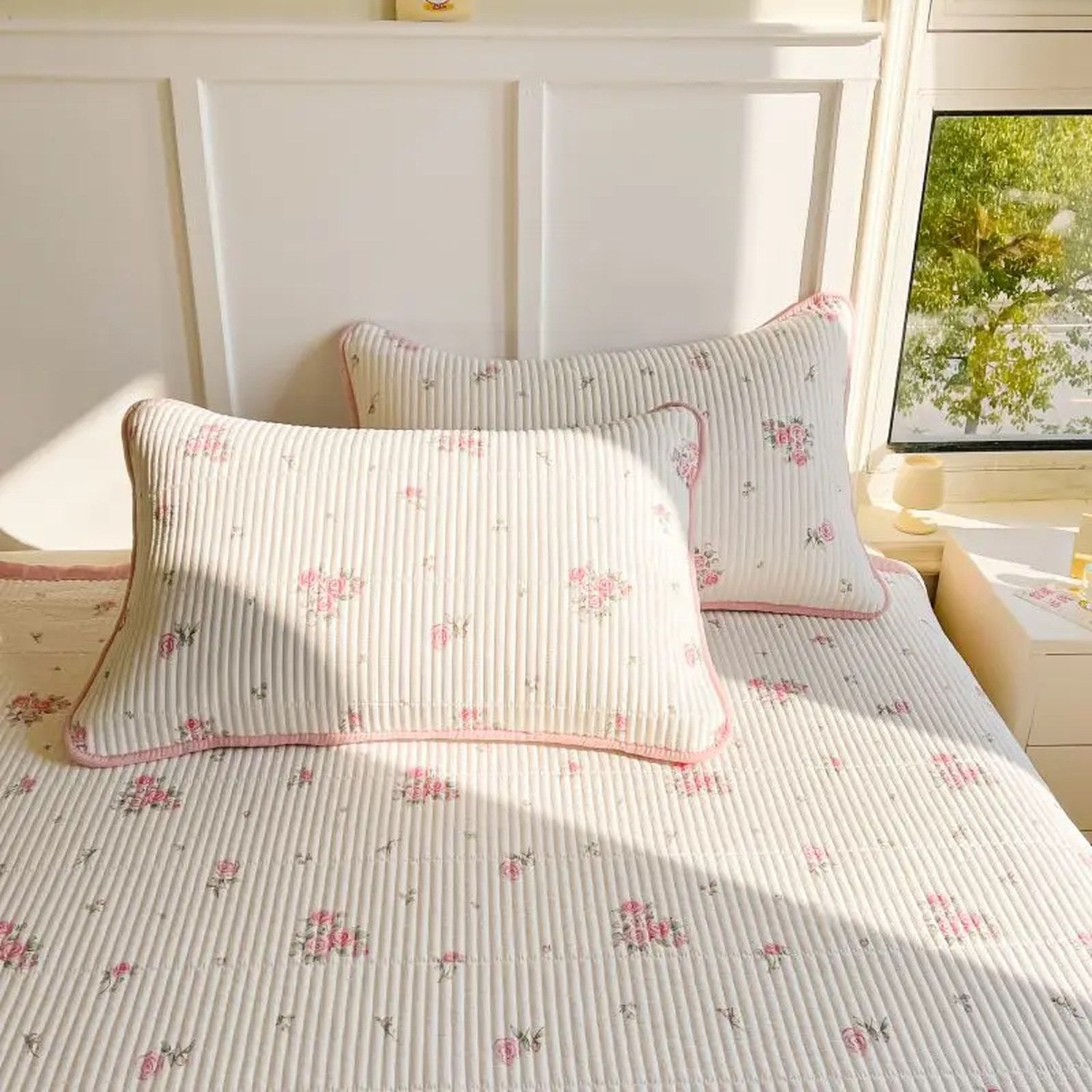 Couvre-lit fleuri et taie d'oreiller posés sur un lit avec un doudou lapin