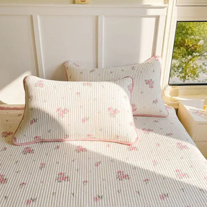 Couvre-lit fleuri et taie d'oreiller posés sur un lit avec un doudou lapin