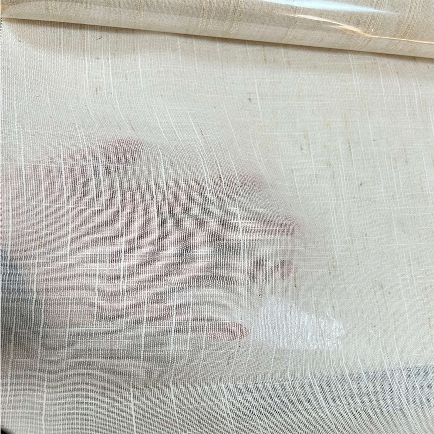 Main posée derrière le tulle transparent illustrant la finesse du tissu