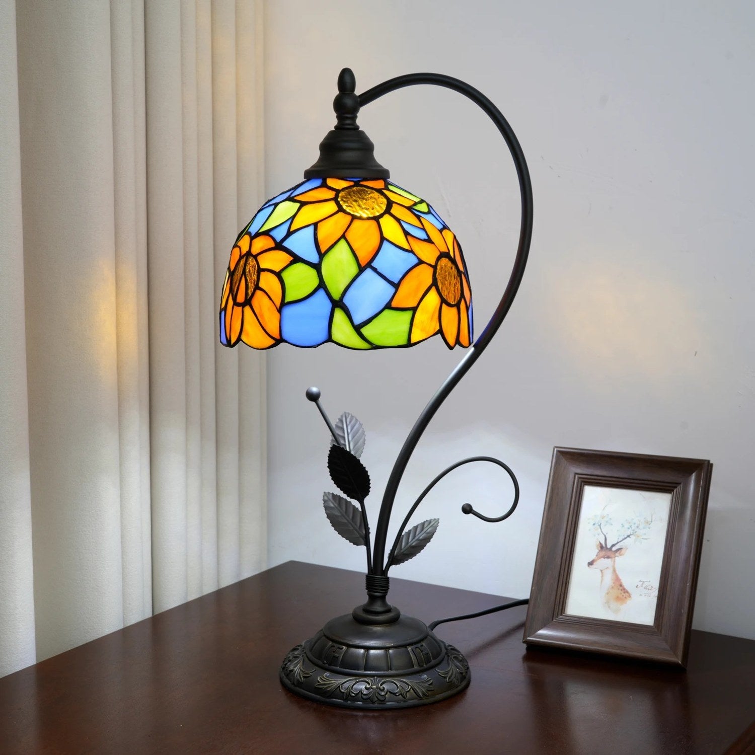 Lampe de table style Tiffany posée sur une table de chevet en bois avec cadre photo