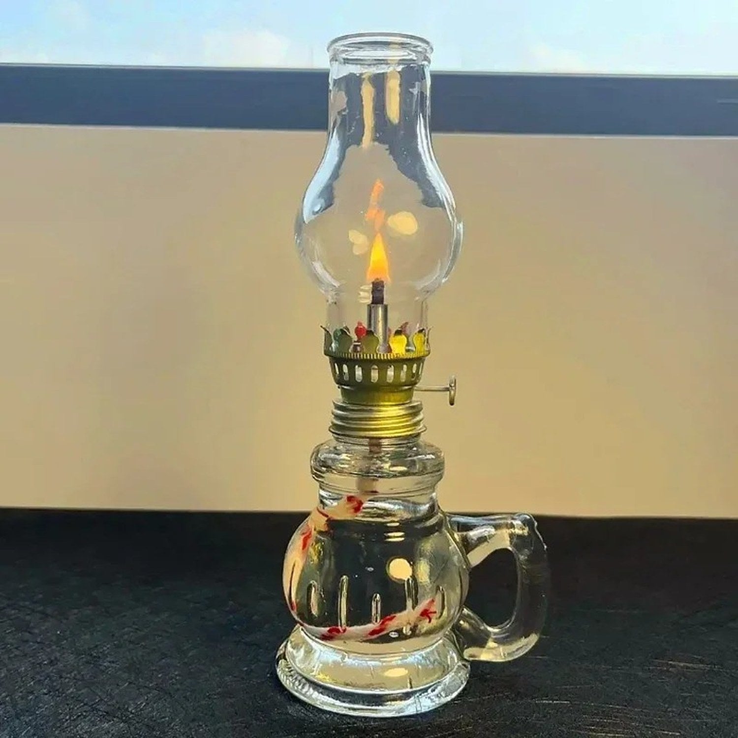 Lampe à pétrole en verre allumée avec flamme visible sur fond chaleureux