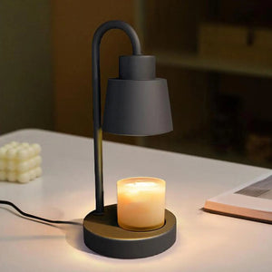 Lampe chauffe-bougie noire posée sur un bureau avec bougie allumée et cire en cube