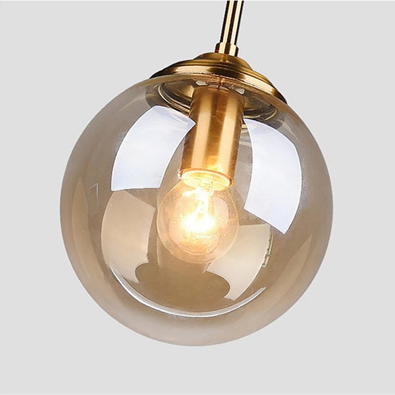Gros plan suspension globe en verre ambre monture laiton dore ampoule filament allumee